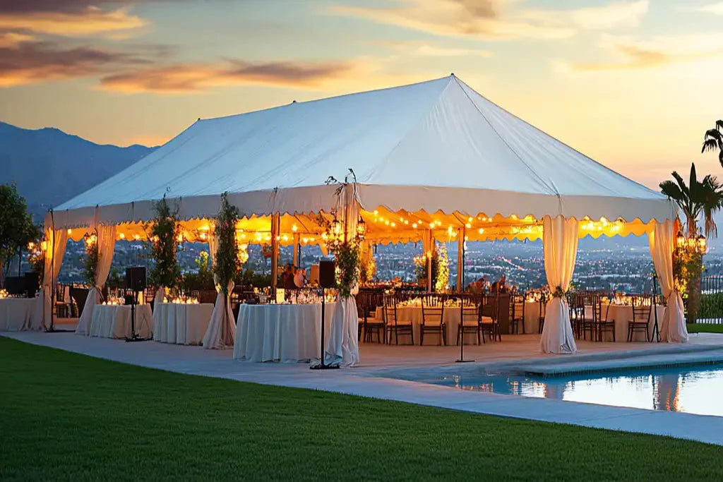 Outdoor event setup with a large white tent by a pool at sunset.